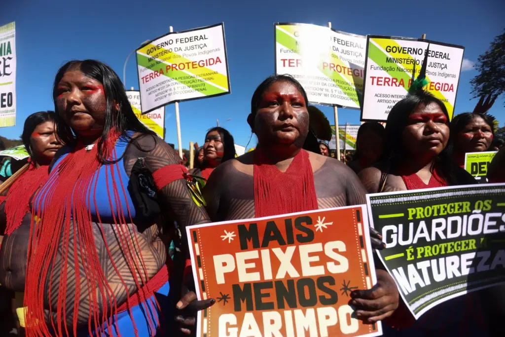 An Indigenous woman marches with a sign that reads in Portuguese 