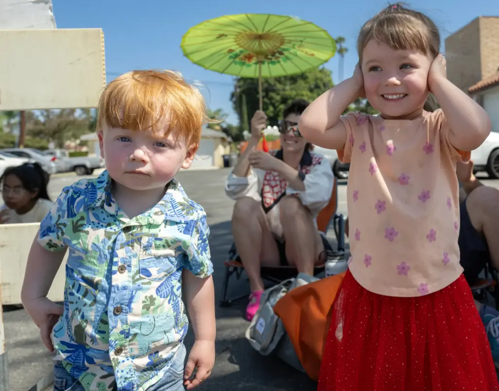Three-year-old Brenna Gibson, with her 1-year-old brother, Canyon, covers her...