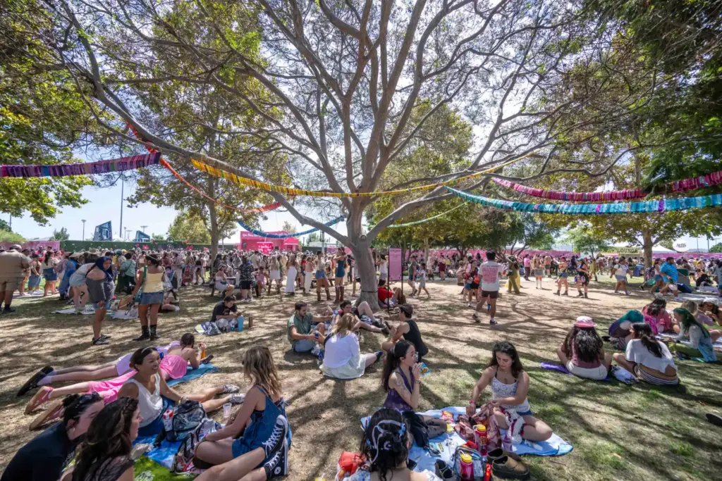 Festivalgoers hide from the sun under the shade of a...