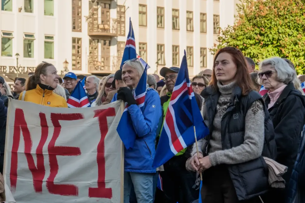 People hold a banner reading “No” as they listen to...