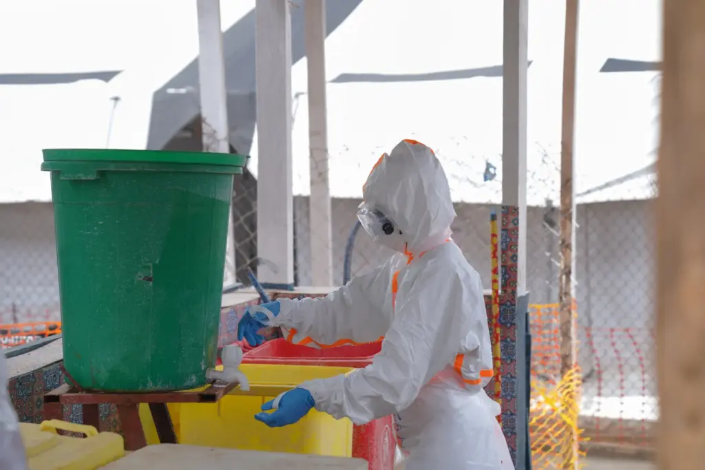 A health worker in protective gear washes her hands.
