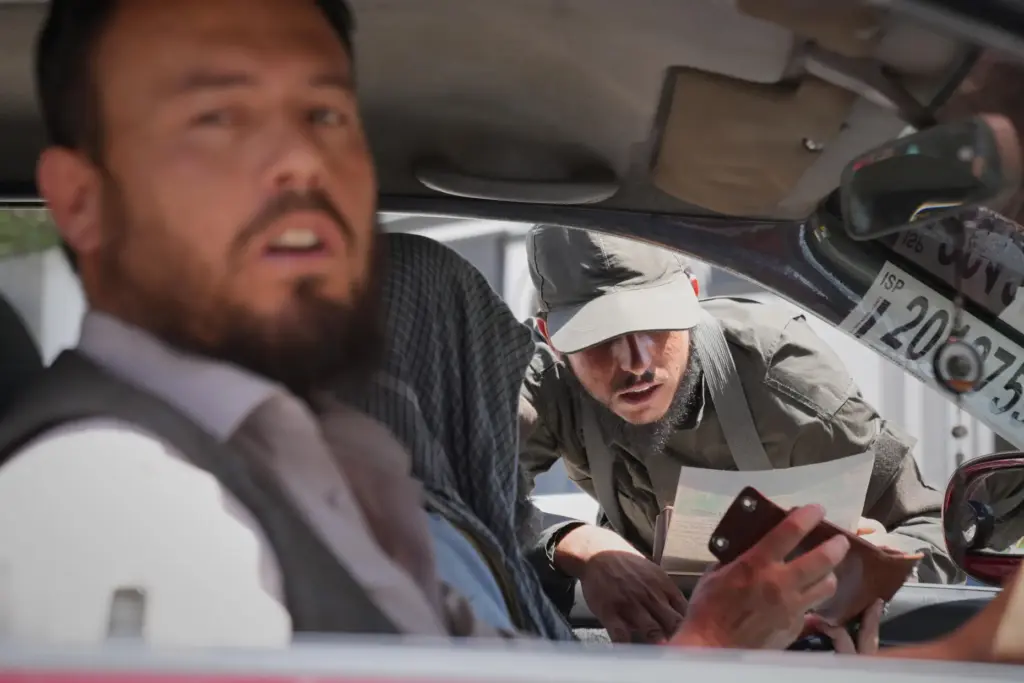 A Taliban security officer checks a driver’s identification at a...