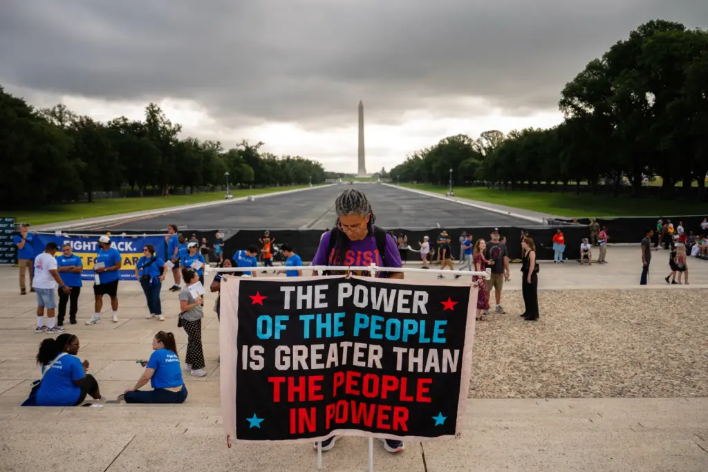 A demonstrator holds a sign in front of the Lincoln Memorial Reflecting Pool.