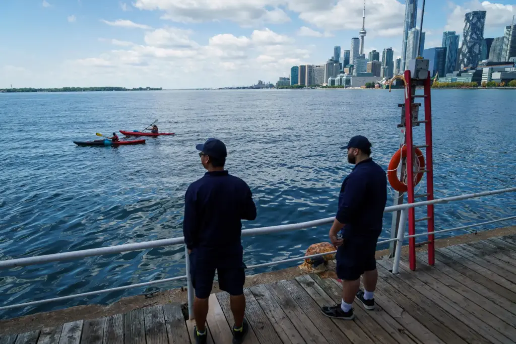 People look out across Lake Ontario from the harbor in...