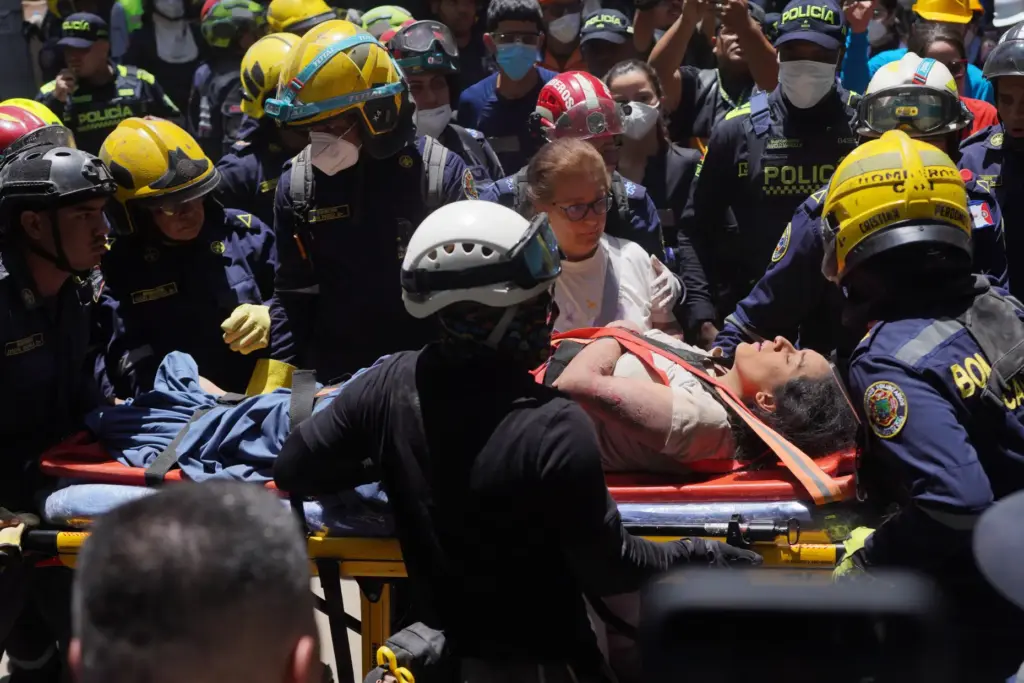 Rescue workers carry Diana Troncoso after pulling her from the rubble.