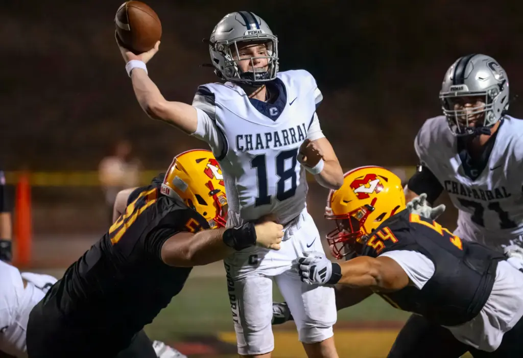 Chaparral quarterback Caden Sterba, center, hurries to get rid of...