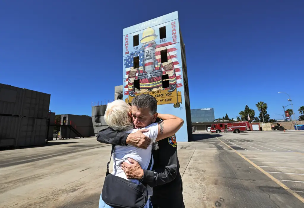 Retired firefighter Fernando Negrete hugs muralist Rosie Tos near the...