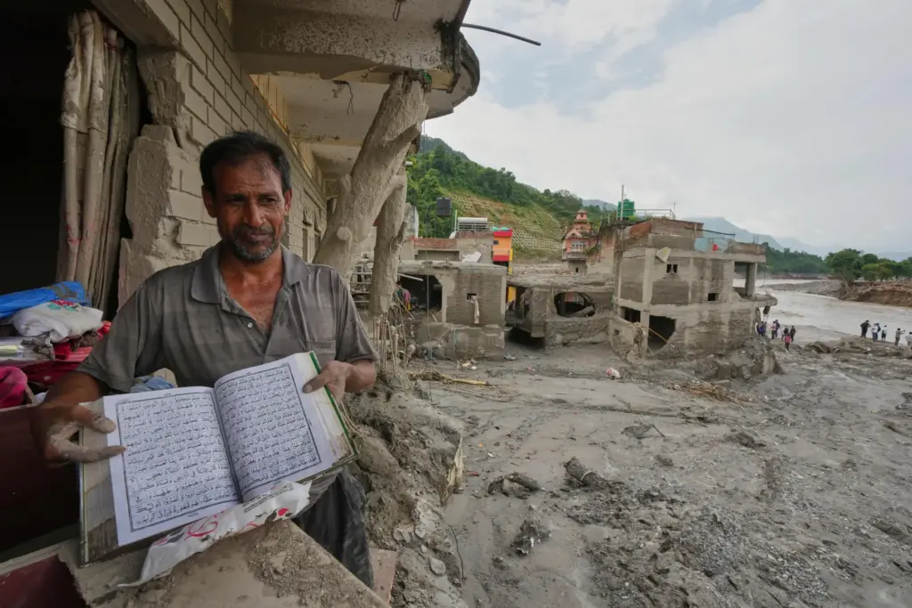 A resident shows a holy book as he salvages his belongings.