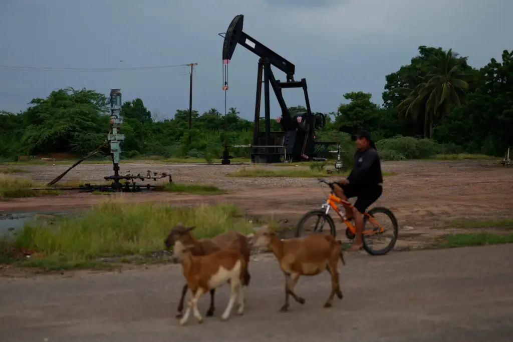 A man rides past an operating oil pumpjack in Cabimas, Venezuela.