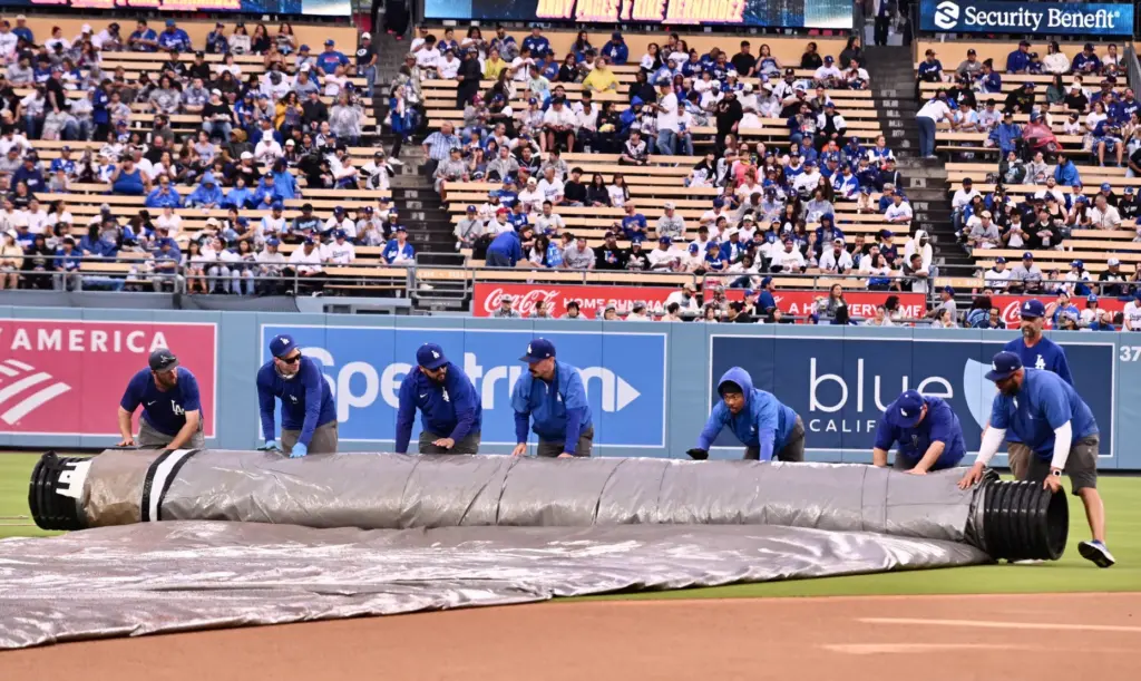 The Dodgers grounds crew rolls up the tarp before the...