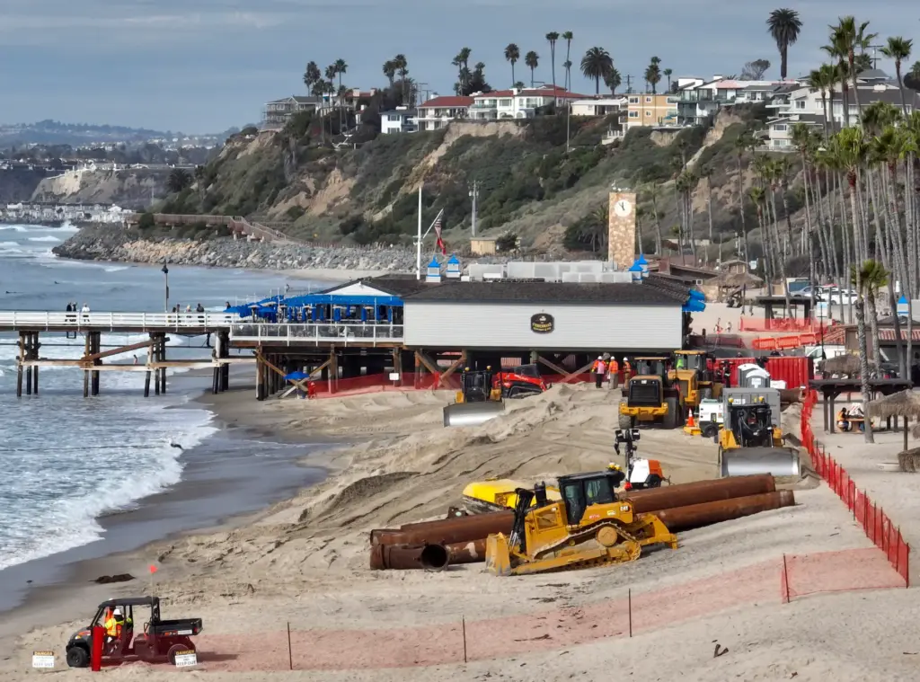 Workers start the long-awaited sand replenishment project near the pier...