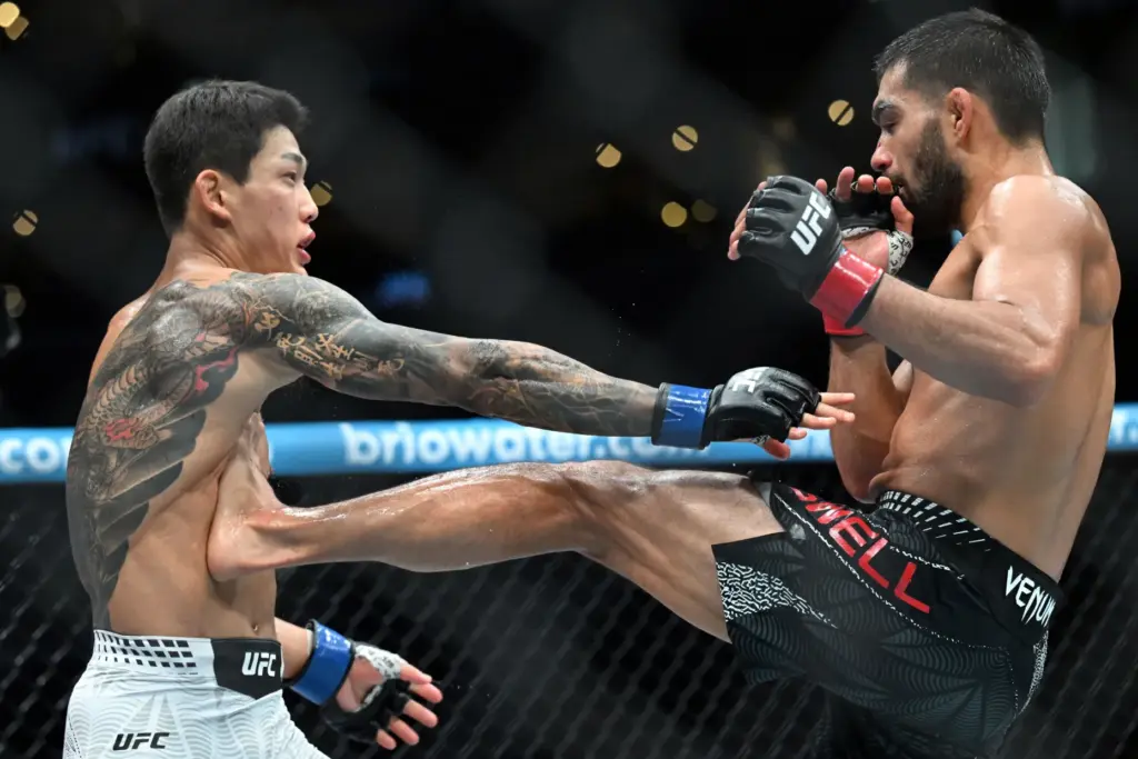 Michael Aswell Jr.(red) lands a kick on Joosang Yoo (blue)...