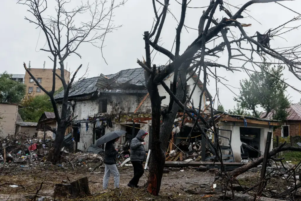 People walk in front of a house that was heavily damaged in a Russian strike in Kyiv.