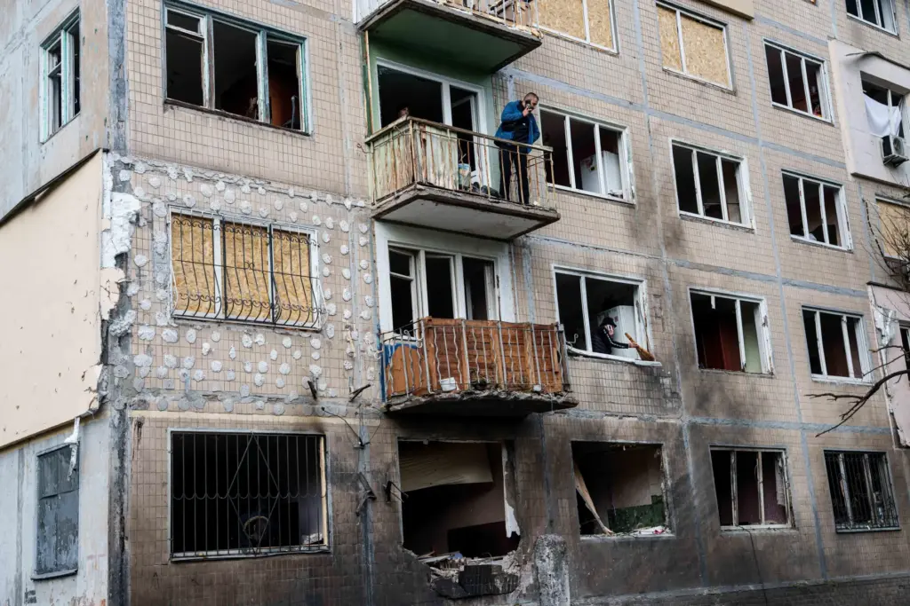 A man stands at a balcony of an apartment building...