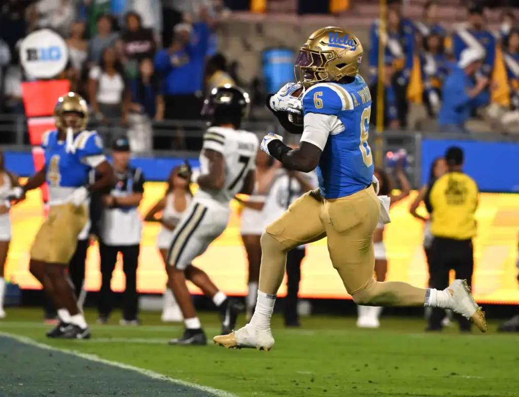 Running back Anthony Woods (6) of the UCLA Bruins runs...