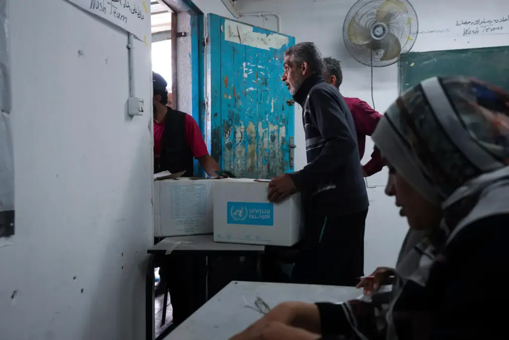 FILE – Palestinians receive aid distributed by UNRWA, the U.N....