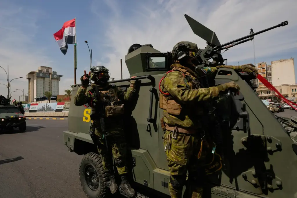 Iraqi police officers stand beside security vehicles decorated with national flags and ribbons.