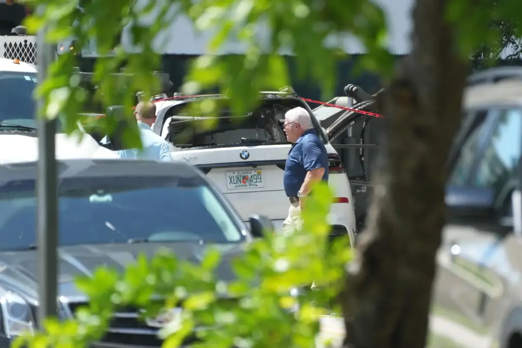 Investigators walk around damaged cars after a large construction crane...