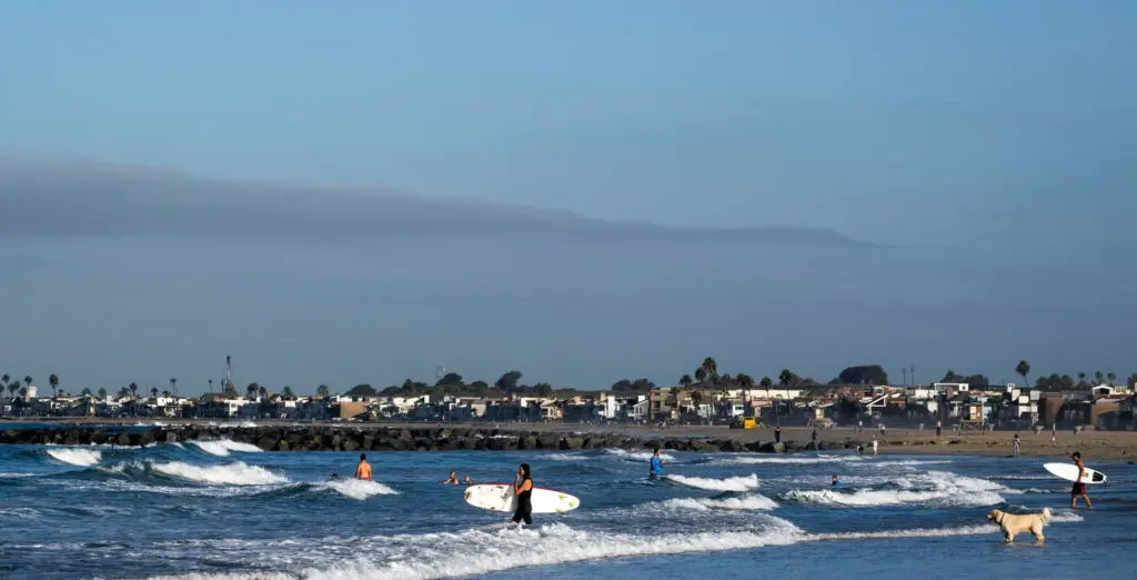 Surfers head to the waves near the Newport Pier in...