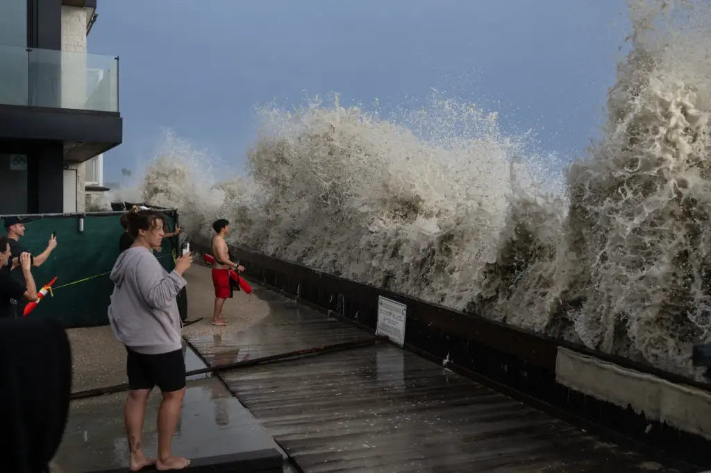 Waves pound a small retaining wall during high tide as...