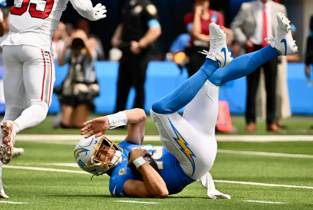 Chargers quarterback Justin Herbert (10) is upended while scrambling for...