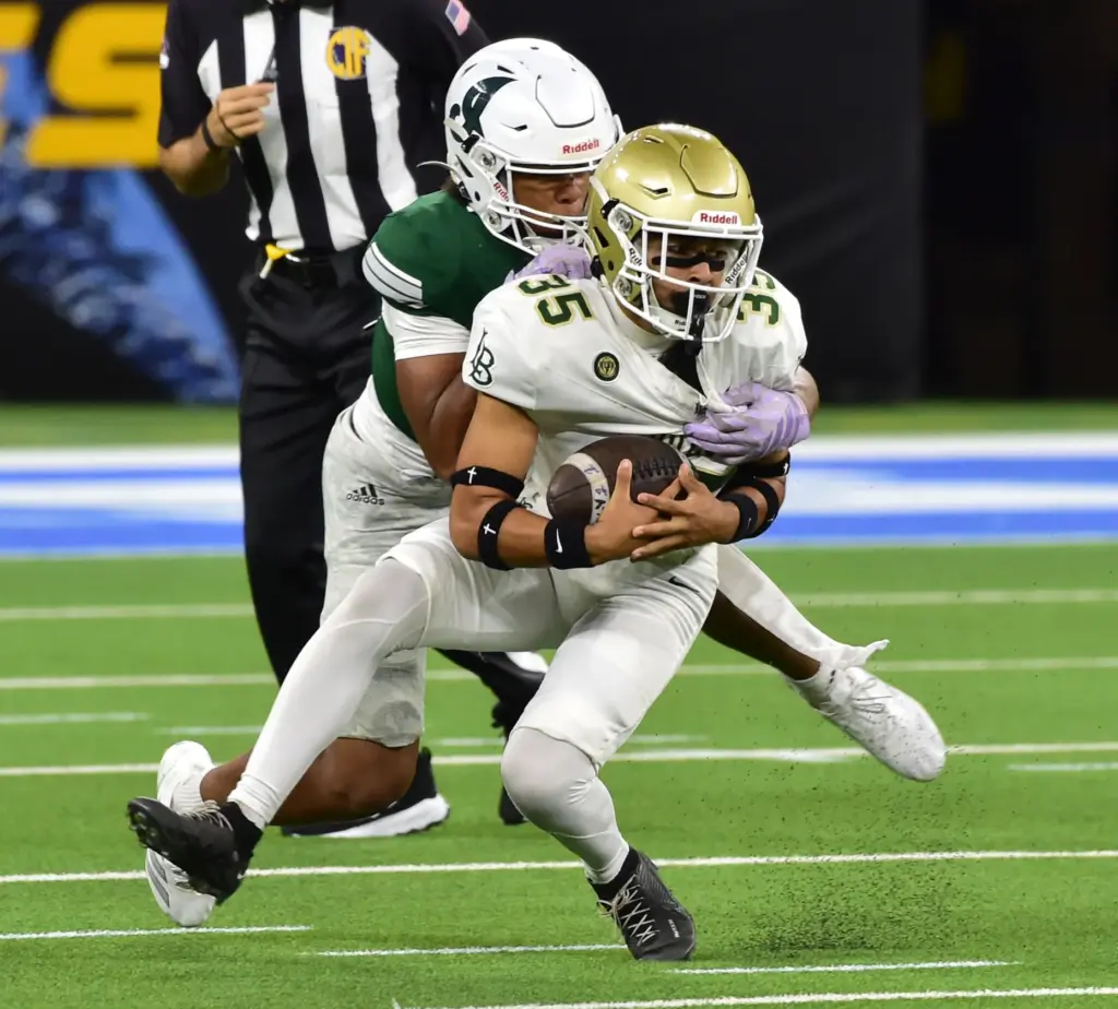 Long Beach Poly punter Jonas Mendoza is tackled by Inglewood’s...