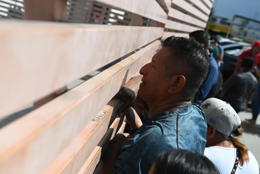 Relatives of crew members of the boat Maria Candelaria peer through a fence.