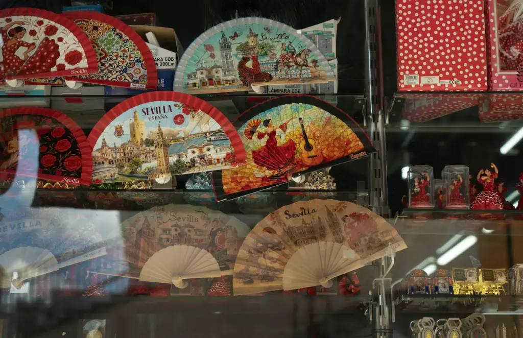 Mass-produced fans featuring tourist images of Seville are displayed.