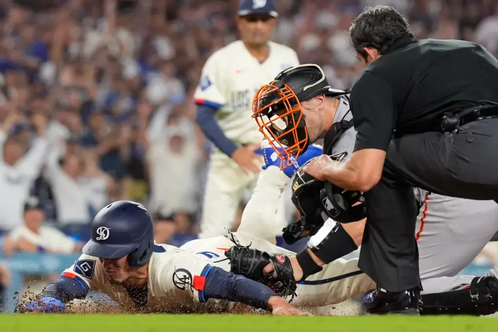 Dodgers’ Tommy Edman, left, is tagged out by San Francisco...