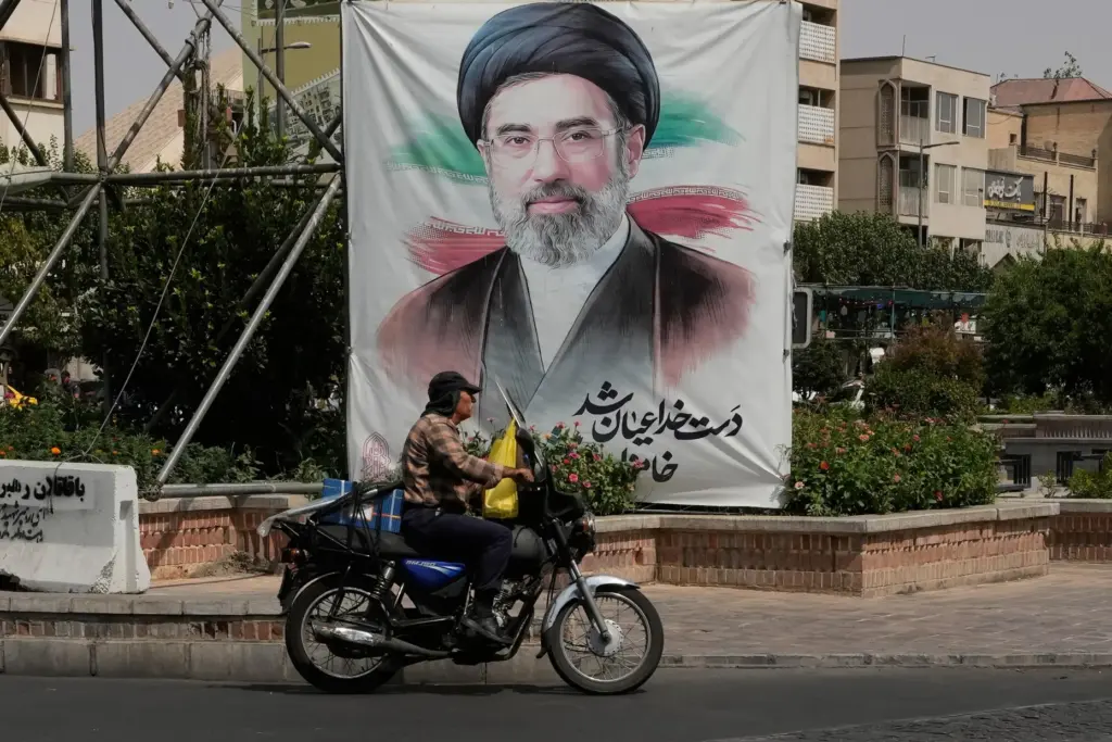 A man drives past a banner of Iranian Supreme Leader Ayatollah Mojtaba Khamenei.