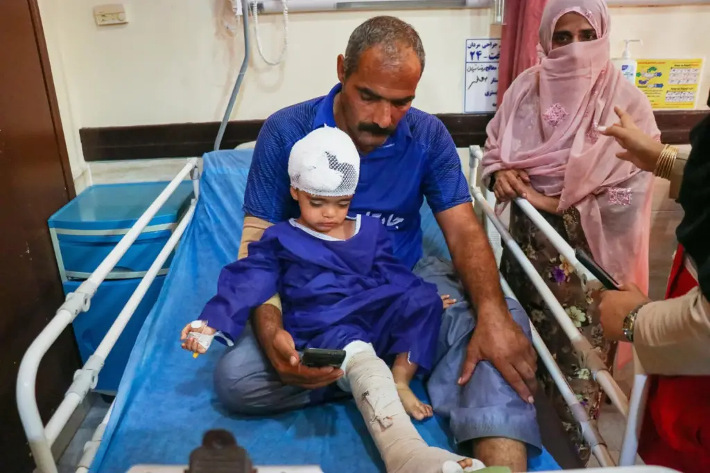 A man sits with a child injured, according to Iranian...