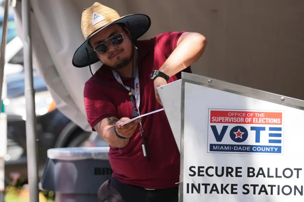 An election worker places a vote-by-mail ballot into a secure bin.