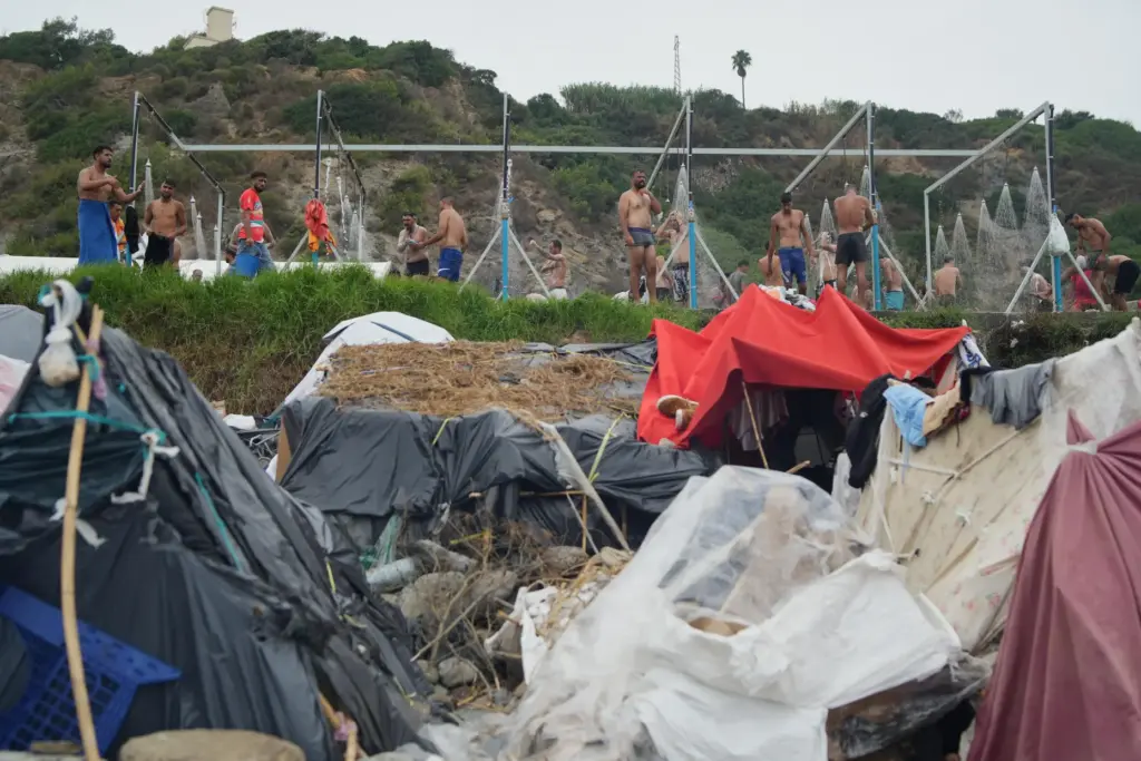 Migrants take a shower near their tents at El Trampolín...