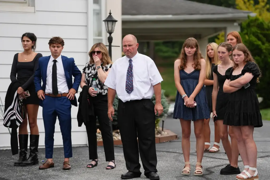 Glenwood Pysher III, watches as pallbearers carry a casket containing...