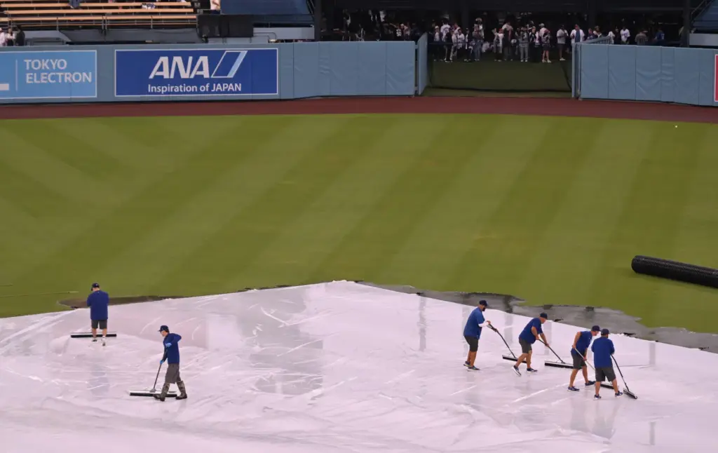 Dodger grounds crew work to clear off water from the...