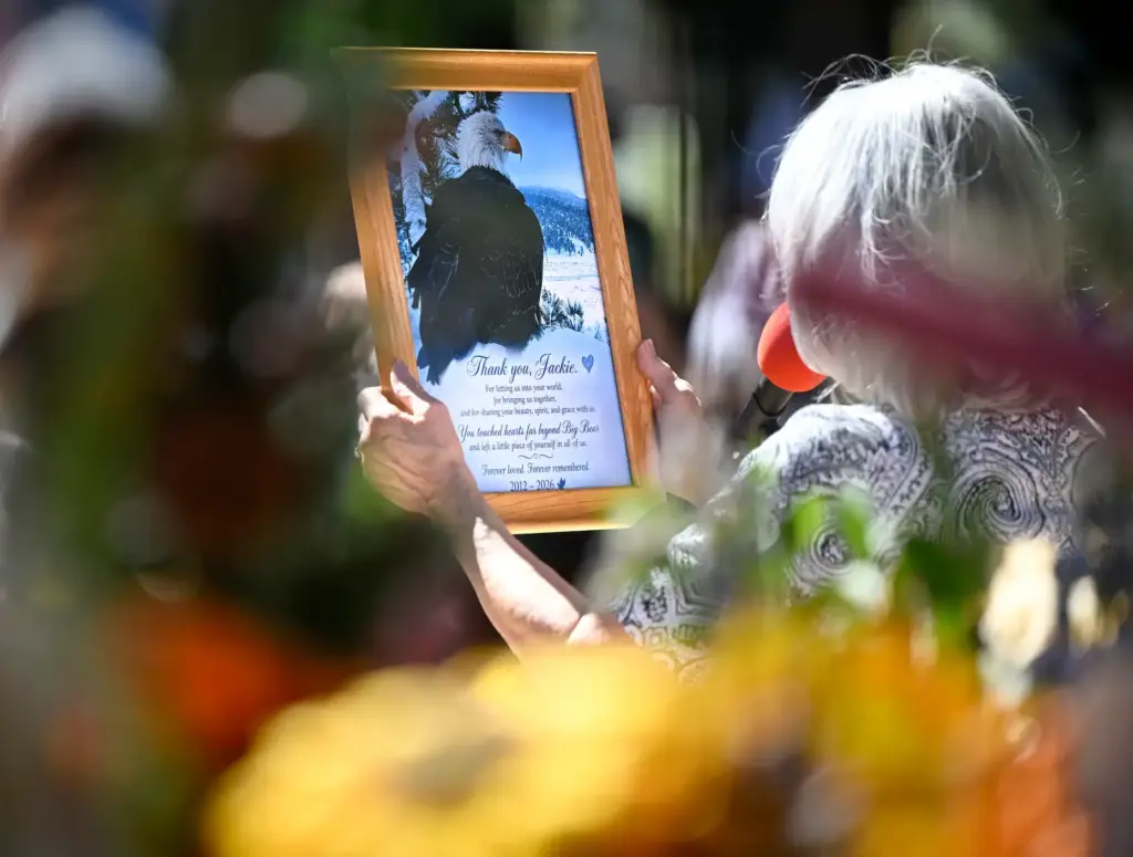 A woman speaks to those gathered as she holds a...