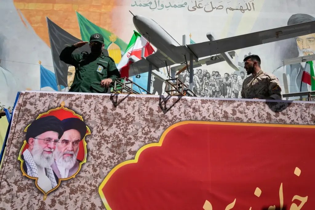 A member of Iran's Revolutionary Guard salutes while riding on a float displaying drones.