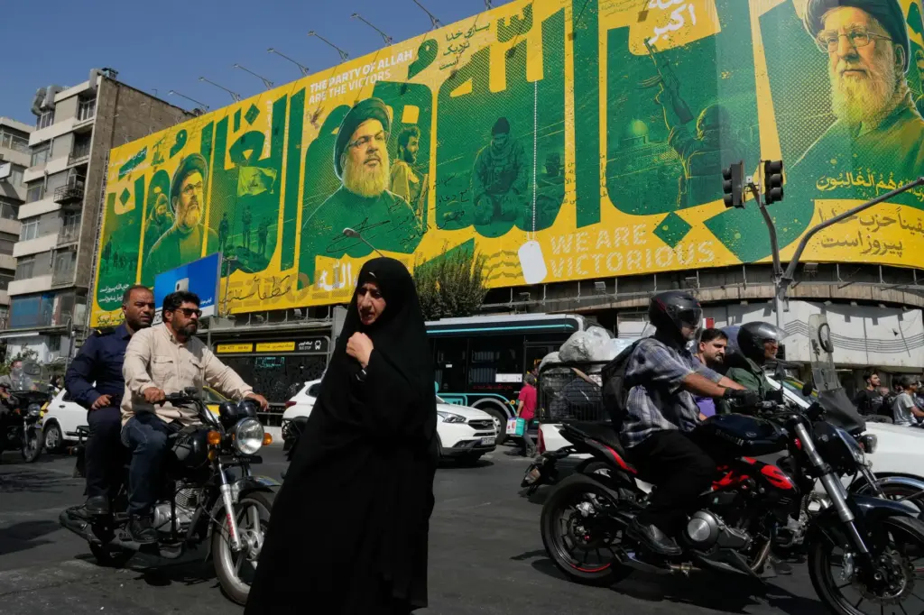 A woman walks and vehicles drive in an intersection in front of a billboard.