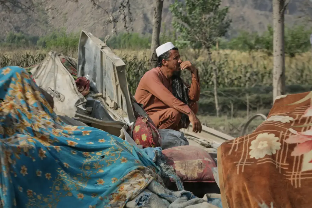 A man sits amid household belongings and the wreckage of...