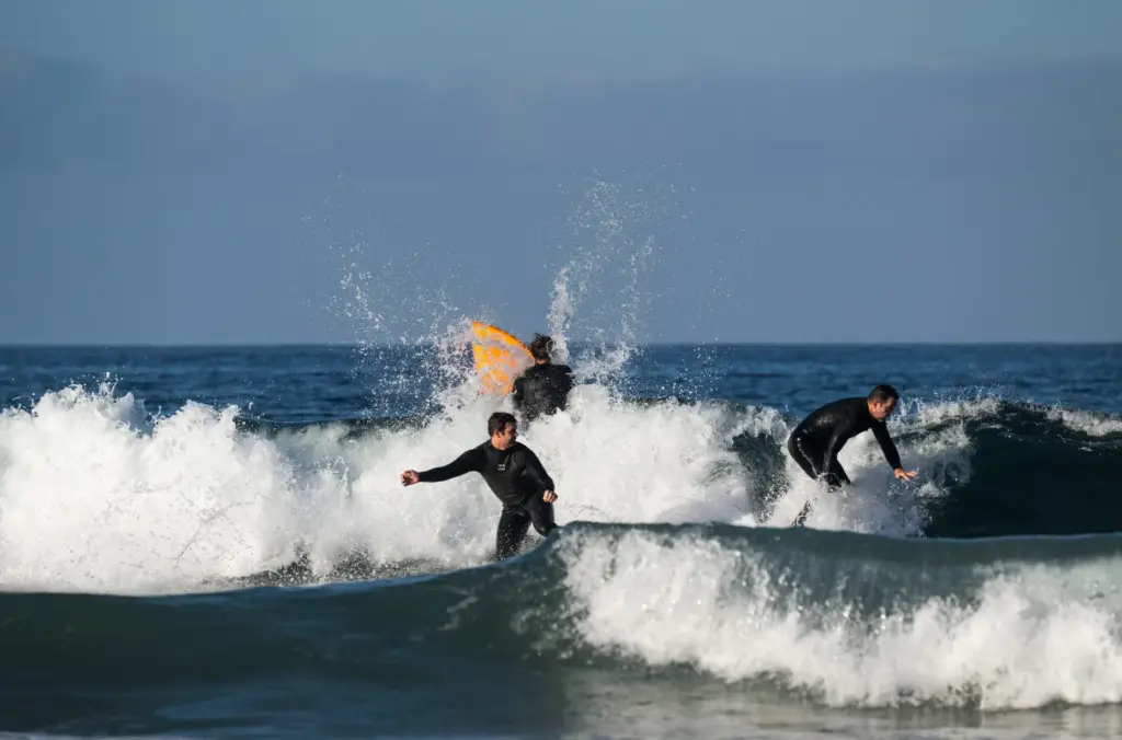 Surfers ride the waves near the Newport Pier in Newport...