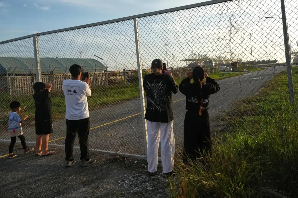 People take pictures as the U.S. Navy aircraft carrier USS Abraham Lincoln arrives.