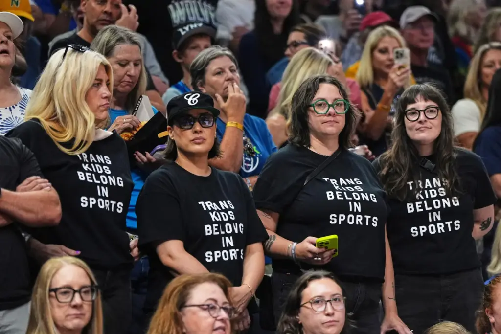 FILE – Fans wear shirts saying, “Trans Kids Belong In...