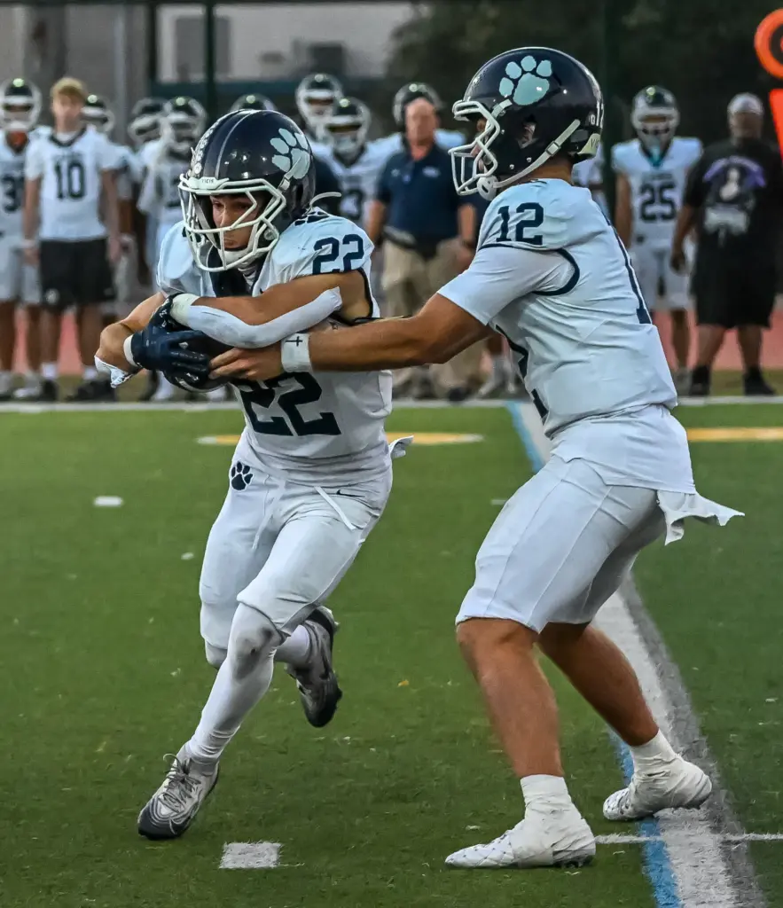 Loyola quarterback JC Rising hands off the ball to running...