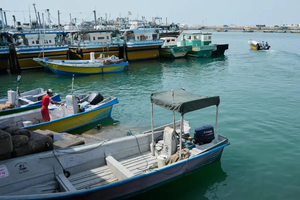 A man works aboard a boat as a motorboat leaves...
