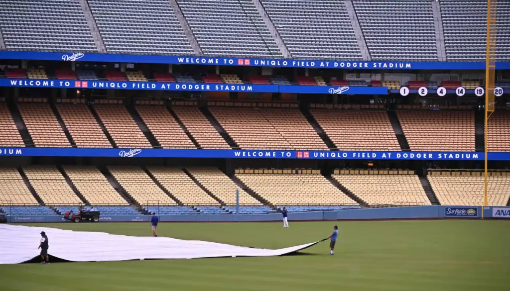 The Dodgers grounds crew pulls the tarp over the field...