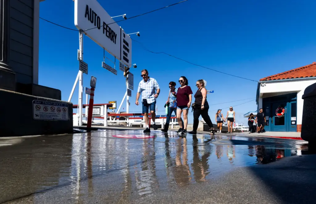 People cross a stream of water coming out of a...