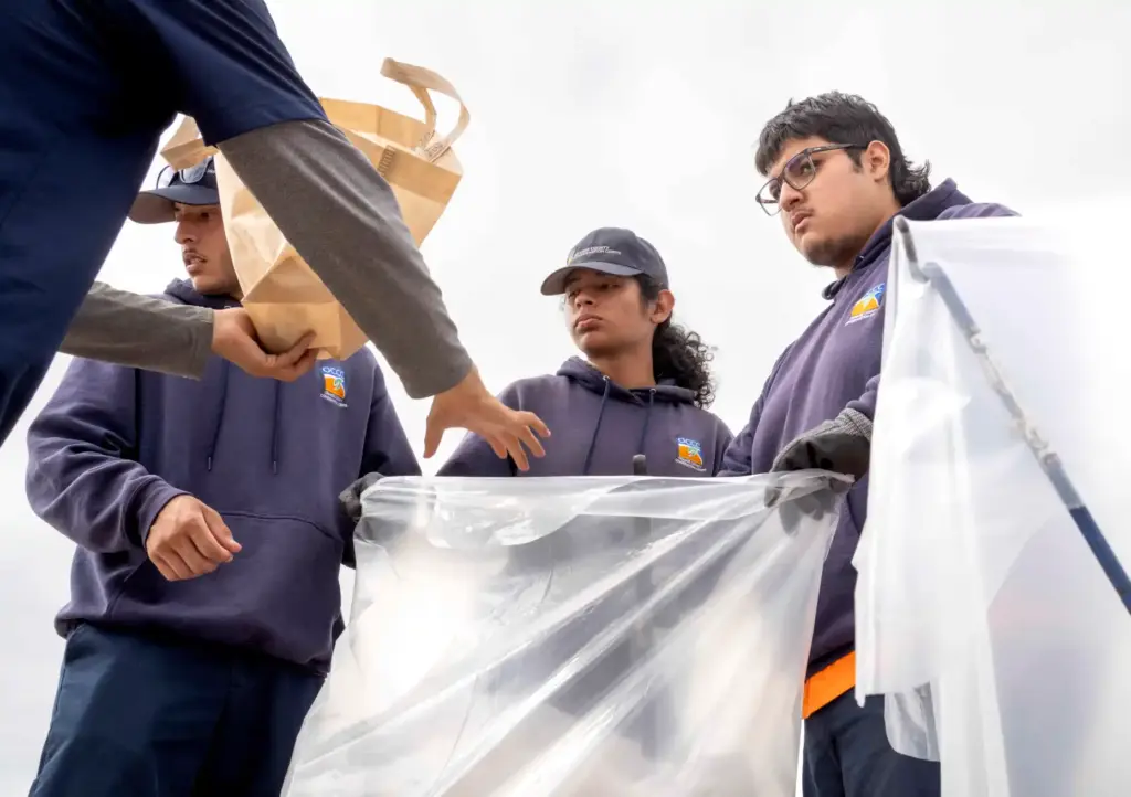Orange County Conservation Corps supervisor Juan Rojas pours trash into...