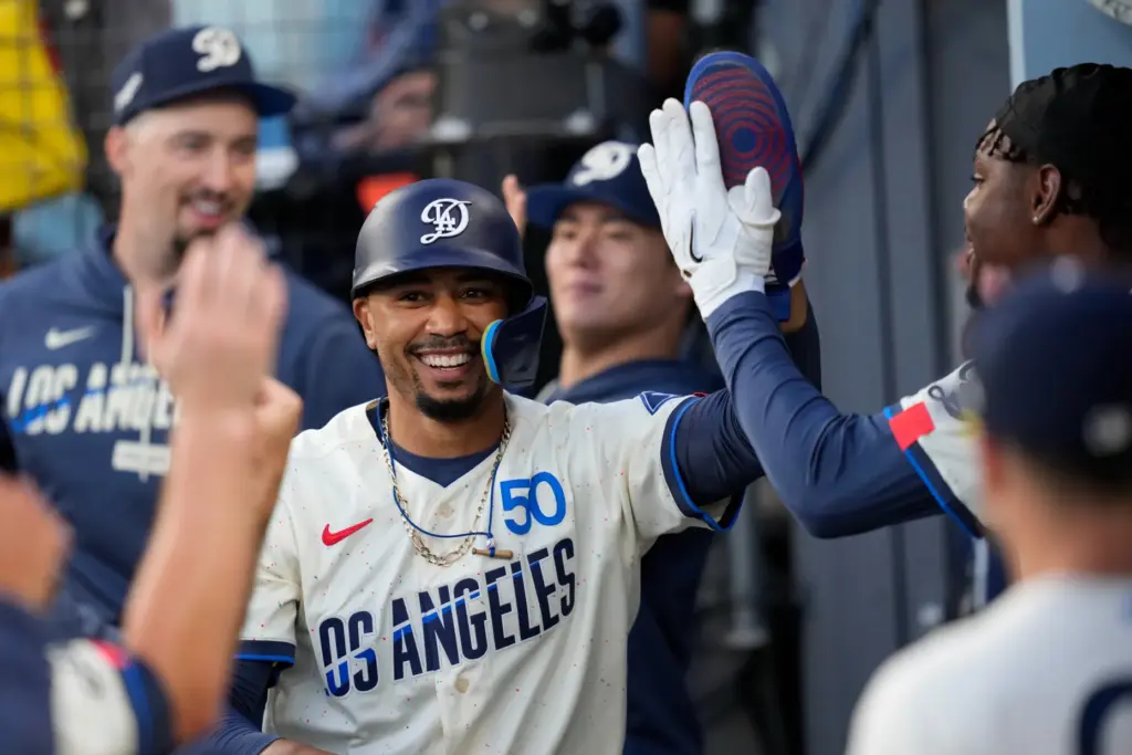Dodgers’ Mookie Betts is congratulated by teammates in the dugout...