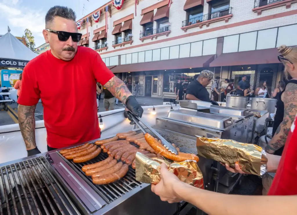 Michael Blan grills Polish Sausages during the first day of...