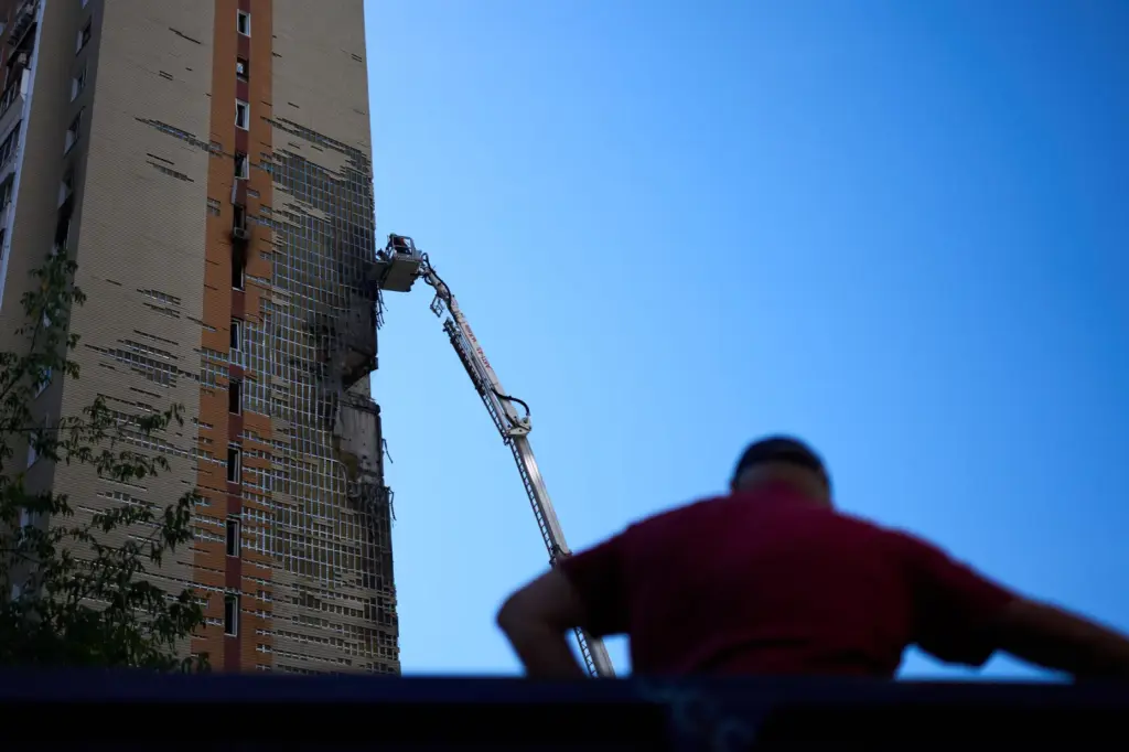 Firefighters work on a partially damaged residential building following a Russian drone attack in Kyiv.